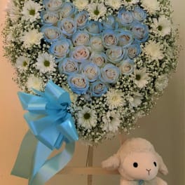 Heart-shaped bouquet of blue roses and white daisies with a blue ribbon