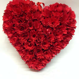 Heart-shaped arrangement of red carnations with a ribbon loop at the top