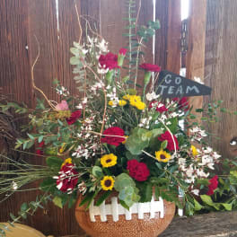 Mixed bouquet in a football-shaped vase with a "Go Team" sign