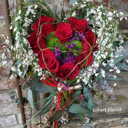 Heart-shaped bouquet of red roses with white blossoms and purple accents