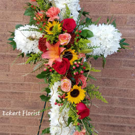 Standing floral cross with white chrysanthemums, red roses, and sunflowers