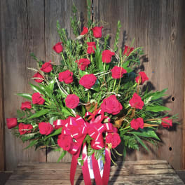 Red roses arranged in a white vase with a pink ribbon bow