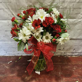Bouquet of red and white flowers in a glass vase with a red ribbon