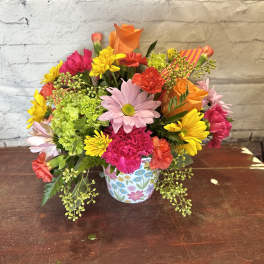 Colorful mixed flower bouquet in a floral-patterned mug
