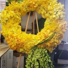 Yellow floral wreath on a wooden easel with trailing greenery