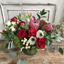 Bouquet of red roses and pink protea in a green vase
