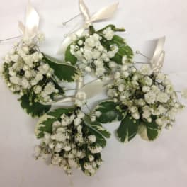 White baby’s breath corsages with cream ribbon and variegated leaves