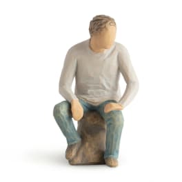 Wooden figurine of a seated person on a rock