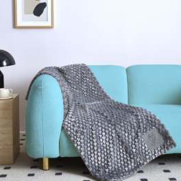 Gray knitted blanket draped over a light blue sofa in a living room