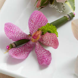 Pink speckled orchid boutonniere with a green accent flower