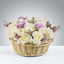 Low basket of white roses with touches of lavender and pink flowers