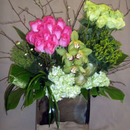 Pink roses and green orchids in a square vase with branches