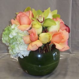 Bouquet of peach roses and pale hydrangea in a dark green vase