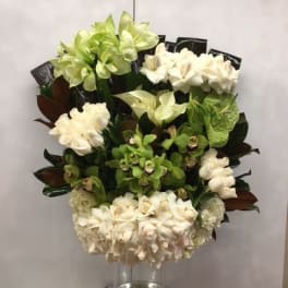 Tall arrangement of green and white orchids in a clear glass vase