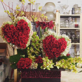 Heart-shaped red rose arrangements with orchids in a decorative box
