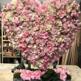 Heart-shaped pink floral arrangement on a rectangular base