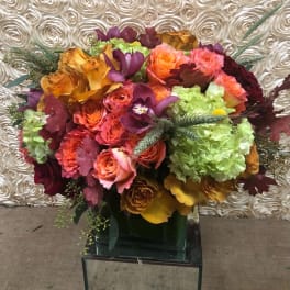 Bouquet of roses, orchids, and hydrangeas in a glass vase