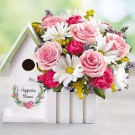 Pink roses and white daisies arranged in a white birdhouse planter