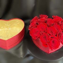Heart-shaped box filled with red roses beside an empty matching box