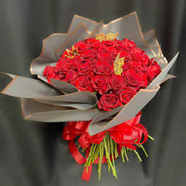 Bouquet of red roses wrapped in gray paper with a red ribbon