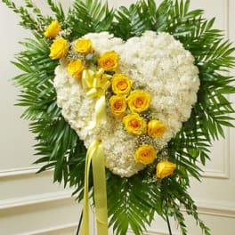 Heart-shaped white floral spray with yellow roses and ribbon