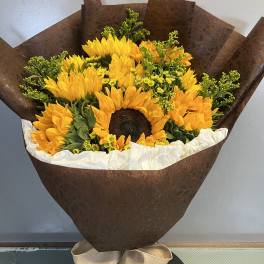 Bouquet of yellow sunflowers wrapped in brown paper with a beige bow