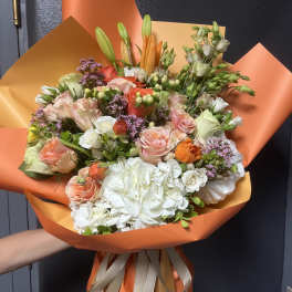 Bouquet of pink, white, and orange flowers wrapped in orange paper