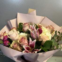 Bouquet of pink roses and lilies wrapped in pale pink paper