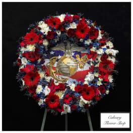 Red, white, and blue floral wreath on an easel with a patriotic emblem in the center
