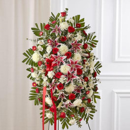 Standing floral spray with red and white flowers on a ribboned easel