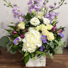 White and lavender floral arrangement in a square vase