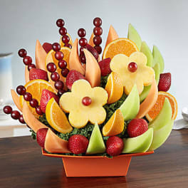Fruit arrangement with orange slices, strawberries, melon, and grapes in an orange container