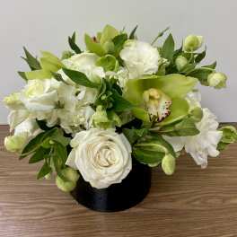 White and green floral arrangement in a black vase