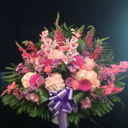 Large pink and lavender floral standing spray with a purple ribbon