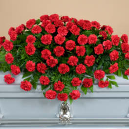 Red carnation spray arranged on a silver casket