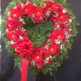 Heart-shaped red floral wreath with a ribbon bow