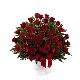 Large arrangement of red roses with red ribbon in a white urn-style vase