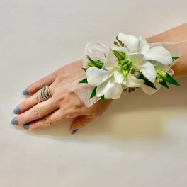 White floral wrist corsage with ribbon on a woman's wrist