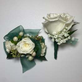 Two white rose boutonnieres with green ribbon and baby's breath