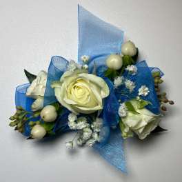 White rose corsage with blue ribbon and small white berries