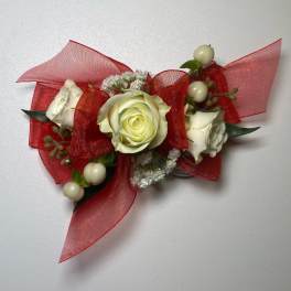 White rose corsage with red ribbon and berry accents
