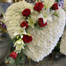 Heart-shaped white floral arrangement with red roses and white lilies