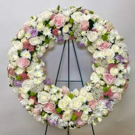 Large circular floral wreath of white, pink, and lavender blooms on an easel