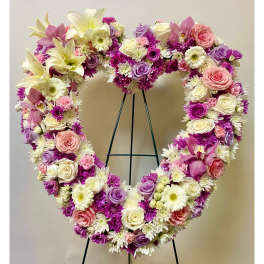 Heart-shaped floral wreath with pink, purple, and white flowers on a stand