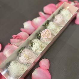 Box of pastel chocolate-covered strawberries with pink rose petals