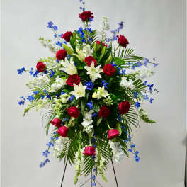 Standing floral spray with red roses, white lilies, and blue flowers