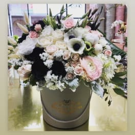 Large mixed bouquet in a round hatbox with pink, white, and black blooms