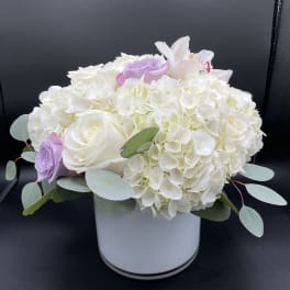 White hydrangea and roses in a white vase with pale purple accents