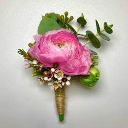 Pink ranunculus boutonniere with small white blossoms and greenery