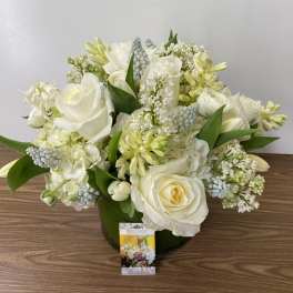 White rose and mixed white flower arrangement in a green vase